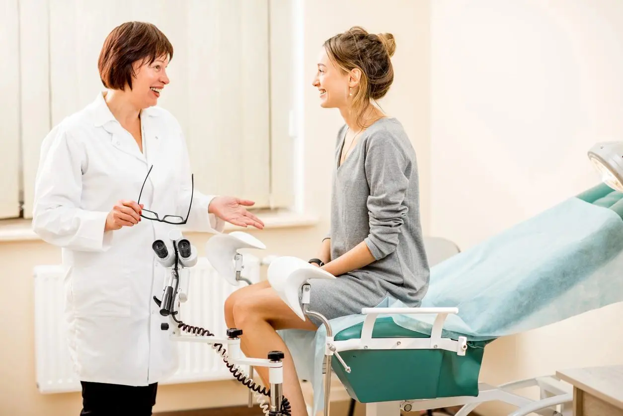 A woman sitting on the chair talking to a doctor.