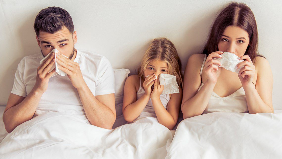 A man and two women lying in bed with one girl.