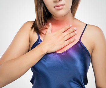 A woman in blue shirt touching her chest.