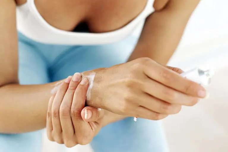 A woman in white shirt holding her hands.