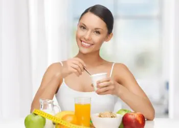 A woman sitting at the table with fruit and cereal.