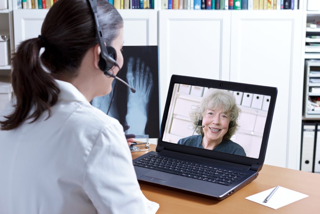 A woman wearing headphones and sitting in front of a laptop.