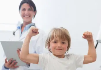 A young girl is flexing her muscles in front of a doctor.