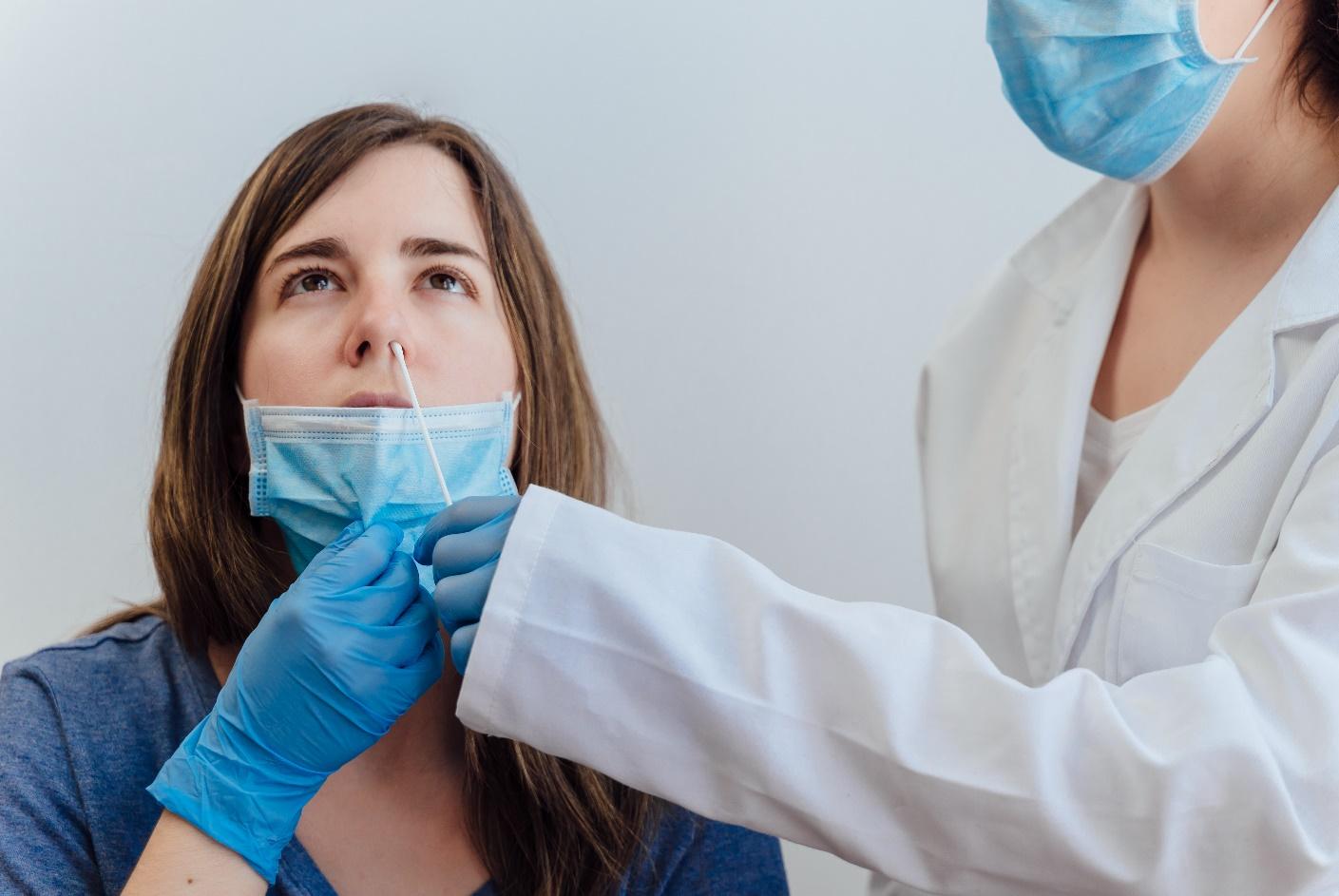 A woman getting her nose covered by a doctor.