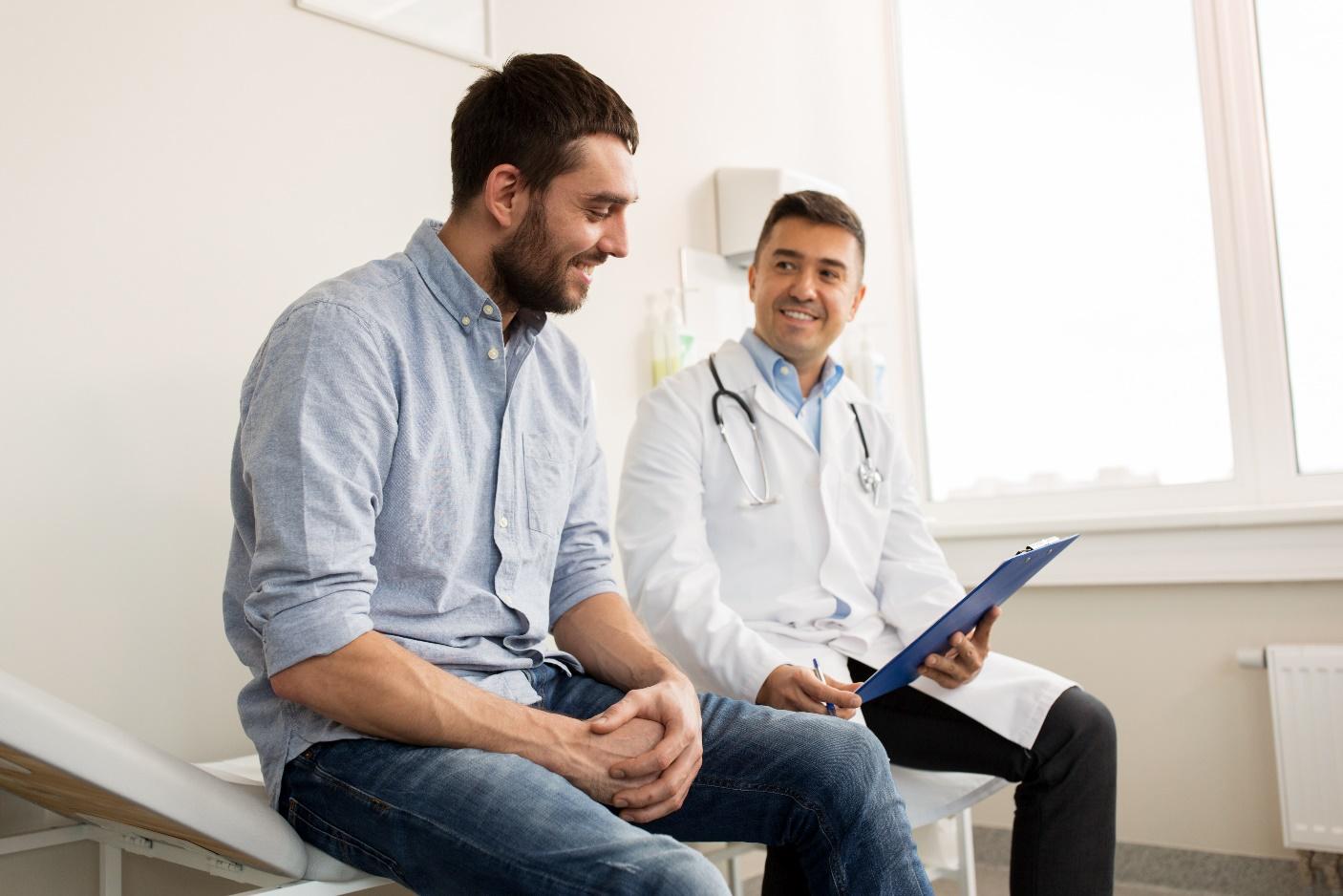 Two men sitting in a room with one of them holding papers.