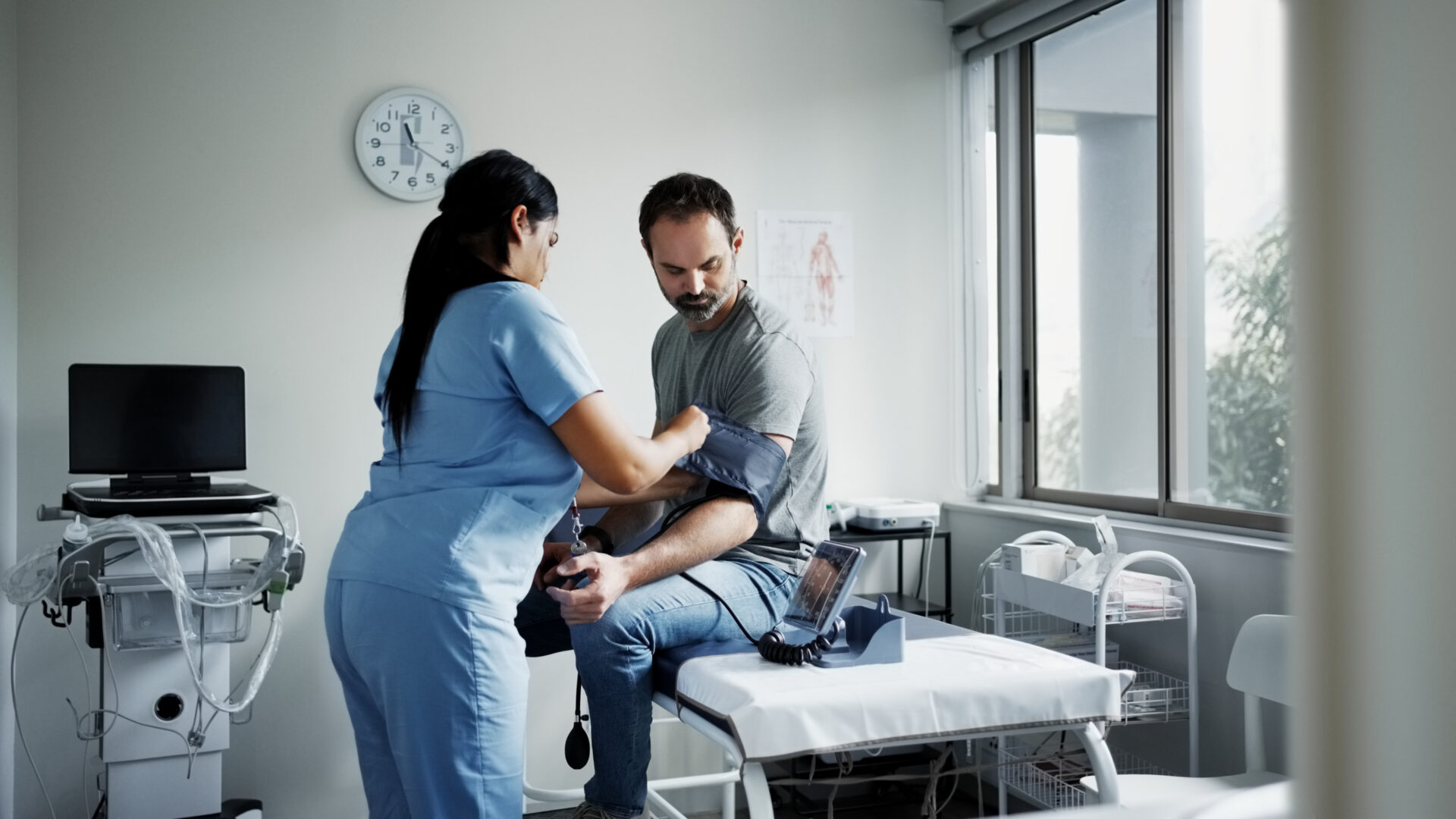 Nurse checking patient's blood pressure in clinic.